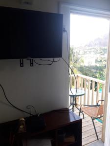 a flat screen tv hanging on a wall next to a balcony at Cosy Corner in Saint Georgeʼs