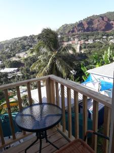 a balcony with a table and a palm tree at Cosy Corner in Saint Georgeʼs