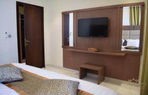 فندق حياة الأصايل في جدة: غرفة نوم مع تلفزيون على جدار مع سرير