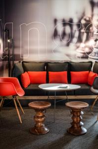 un sofá con almohadas de color naranja, mesa y sillas en ibis Paris La Defense Courbevoie en Courbevoie
