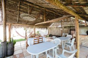 a patio with tables and chairs in a building at Pousada Recanto Verde in Parajuru