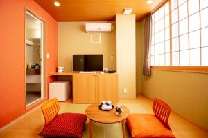 a living room with a table and chairs and a television at Nagomi Hotel Nippori in Tokyo