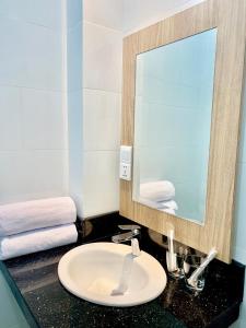a bathroom with a sink and a mirror and towels at Bintan Lumba Lumba Inn Hotel in Tanjung Pinang 