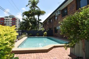 een zwembad in een tuin naast een gebouw bij Wunpalm Motel & Cabins - Late check-in available in Maroochydore