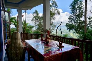 a woman sitting at a table on a porch with a view at Sun View Resort Kithalella in Ella