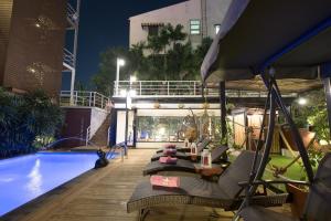 eine Terrasse mit Stühlen und ein Pool in der Nacht in der Unterkunft Siam Piman Hotel in Bangkok