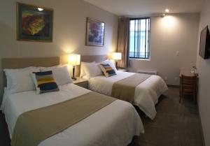 a hotel room with two beds and two lamps at Hotel Le Deville in Montreal