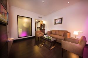 a living room with a couch and chairs and a tv at AnCasa Hotel Kuala Lumpur, Chinatown by AnCasa Hotels & Resorts in Kuala Lumpur