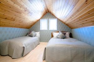 two beds in a room with a wooden ceiling at tocoro. Mt. Fuji Mutsuki in Fujikawaguchiko