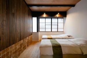 1 dormitorio con 2 camas y ventana en Machiya Hotel YANAGI, en Kioto