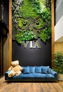 a teddy bear sitting on a blue couch in front of a plant at Via Hotel Taipei Station in Taipei