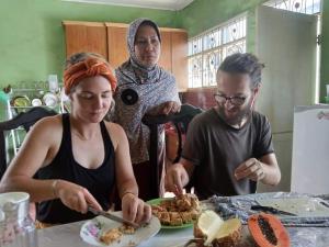 不拉士打宜Kaesa Homestay的一群人站在桌子旁吃食物