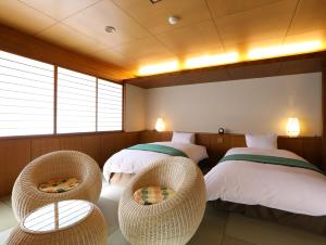 a room with two beds and wicker chairs at Hotel Tamanoyu in Matsumoto