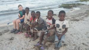 a group of children sitting on the beach at Gateway Guest House in Monkey Bay