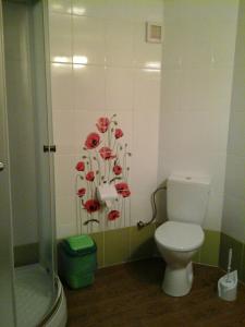 a bathroom with a toilet and red flowers on the wall at Hotel Коттедж Leleka Vyzhnynsia in Rivna