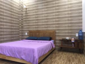 1 dormitorio con 1 cama con manta morada en Ruby Dalat Hostel, en Da Lat