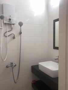 uma casa de banho branca com um lavatório e um chuveiro em Ruby Dalat Hostel em Da Lat