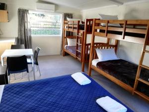 Schlafsaal mit Etagenbetten, einem Tisch und einem Tisch in der Unterkunft Mawley Holiday Park in Masterton