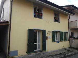 a yellow house with green shutters and a door at Casa Camilla in Viareggio