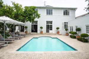 a swimming pool in front of a white house at River Manor Boutique Hotel by The Living Journey Collection in Stellenbosch