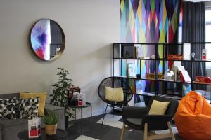 sala de estar con sofá, sillas y espejo en Ibis Styles Crolles Grenoble A41, en Crolles