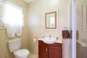 een badkamer met een toilet, een wastafel en een spiegel bij Ocean Breeze Bloubergstrand in Bloubergstrand