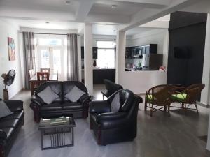 a living room with black leather furniture and a kitchen at Twin Villa 22 in Katugastota