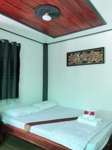 a bedroom with a bed with a wooden ceiling at Moat View in Sukhothai