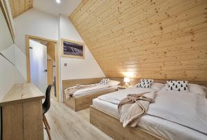 two beds in a room with a wooden ceiling at Apartamenty Kościelisko in Kościelisko