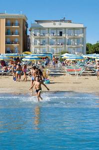 un grupo de personas jugando en el agua en la playa en Residence Roxy, en Misano Adriatico
