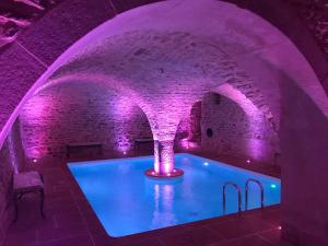 una piscina coperta con illuminazione viola in un edificio di Domaine de la Corgette a Saint-Romain