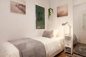 Dormitorio blanco con cama y lámpara en Rambla Poblenou&Mar Bella Beach, en Barcelona