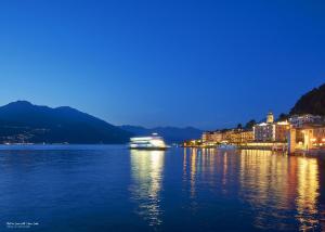 a boat on the water in a city at night at Fall In Love with Como Lake in Bellano