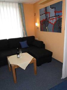 a living room with a black couch and a table at Am Maiglöckchenberg 19 in Ostseebad Karlshagen