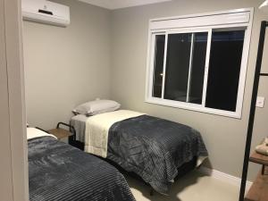 1 dormitorio con 2 camas y ventana en Ocean Life, en Florianópolis