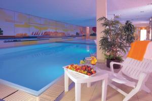 a swimming pool with a bowl of fruit on a table in front of it at Ringhotel Loew's Merkur in Nuremberg