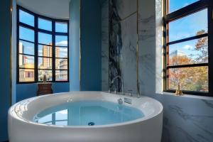 a large tub in a bathroom with two windows at Moon and Chalice Boutique Hotel in Kunming