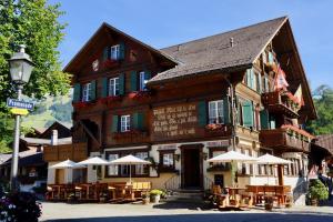a building with tables and umbrellas in front of it at Posthotel Rössli in Gstaad