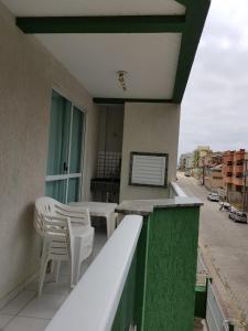 un balcón con sillas blancas y una mesa en un edificio en Residencial Júnior, en Bombinhas