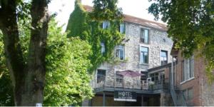 a large brick building with a balcony and a hotel at Hotel La Librairie in Durbuy