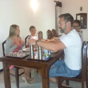 a man sitting at a table with a group of people at Omee Guest in Mirissa