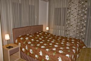 a bedroom with a bed with a bedspread with flowers on it at Hotel Horizontas in Nea Plagia