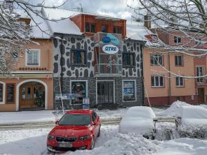 弗林布爾克的住宿－Apartments Otre Frymburk，停在雪覆盖的建筑前面的红色汽车