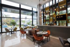 un restaurante con mesas, sillas y ventanas en ibis Styles Izmir Bornova en İzmir