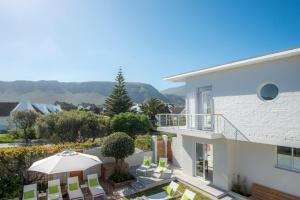 a balcony of a house with chairs and an umbrella at Bamboo Guest House in Hermanus