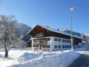 a building covered in snow in front of a mountain at Haus Bamberger in Fischbachau