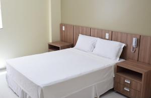 a bedroom with a large white bed with a wooden headboard at ALENCAR HOTEL in Barreiras