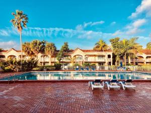 a resort swimming pool with chairs and palm trees at Grand Palms Spa & Golf Resort in Pembroke Pines