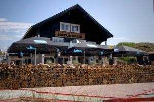 un edificio con sombrillas delante en Beach House Sea-Esta, en Egmond aan Zee