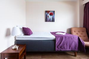 a bedroom with a bed with a purple blanket on it at Hotel Julie in Joensuu